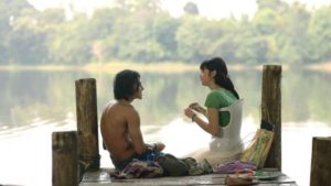 Kadr z filmu Mika przedstawiający głównych bohaterów - Mikę i Indi siedzących nad jeziorem, Mika siedzi w gorsecie na skoliozę. 